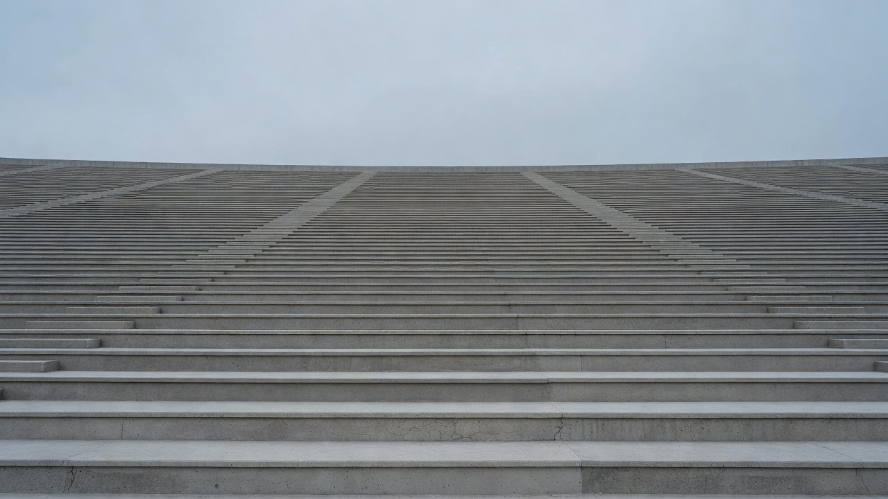 Empty concrete stadium terraces under a soft overcast sky