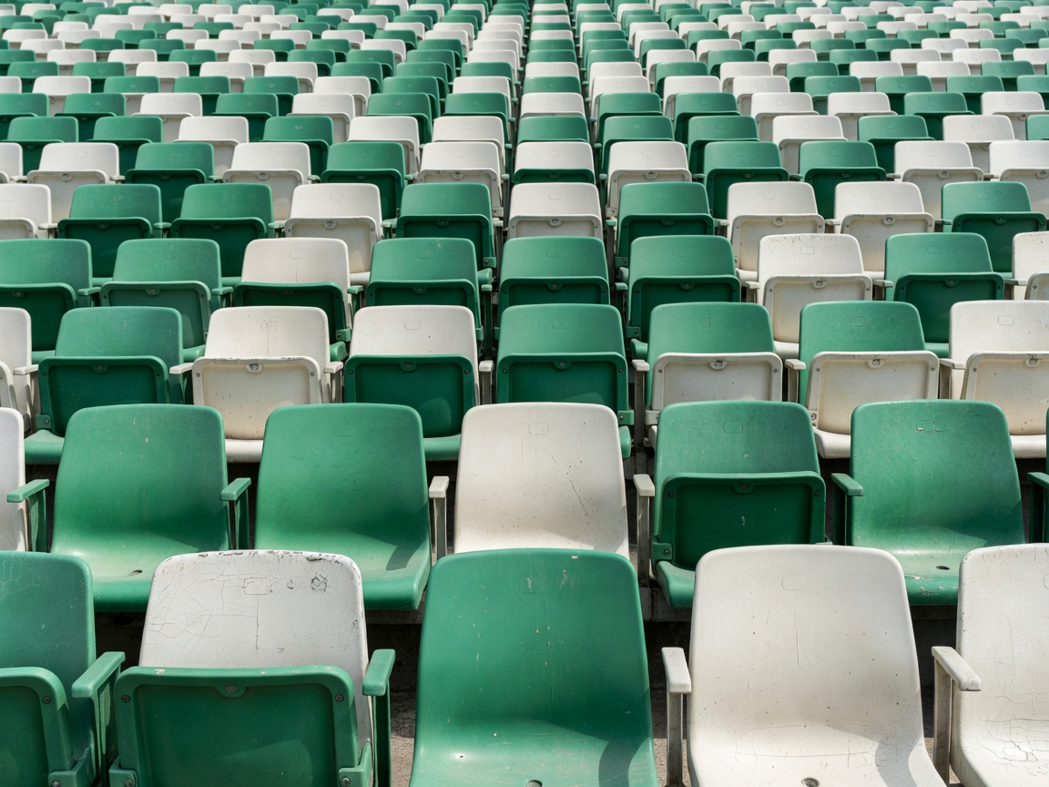 Rows of weathered green and white stadium seats in daylight