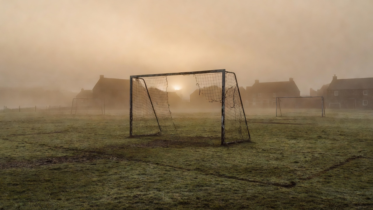 Village football pitch with old goalposts standing in morning mist